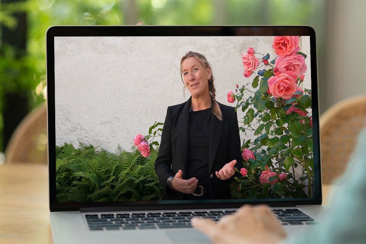 Person sitter vid dator och tittar på en kvinna som pratar.