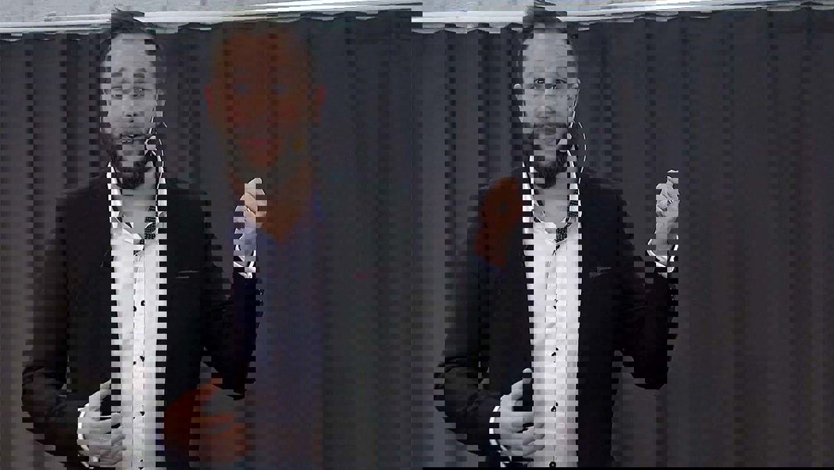 Person i seminariesituation iförd mikrofoneheadset stående framför ett mörkt draperi.