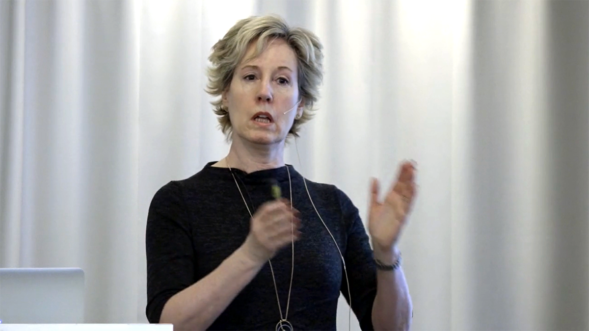 Person med mikrofonheadset framför vitt draperi.