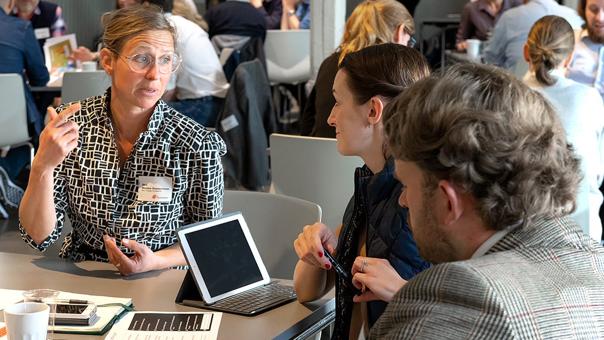 Personer samtalar runt ett bord vid ett seminarium.