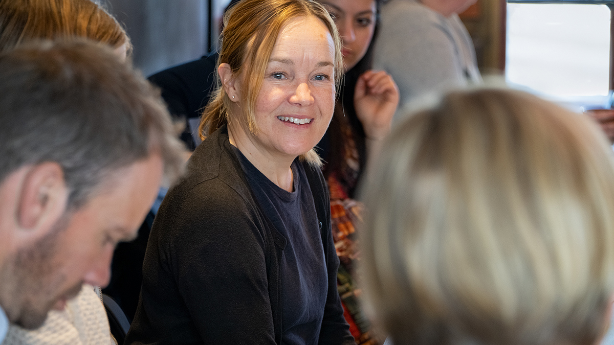 En person lyssnar intensivt på en annan person som pratar i ett rum fyllt av forumdeltagare.