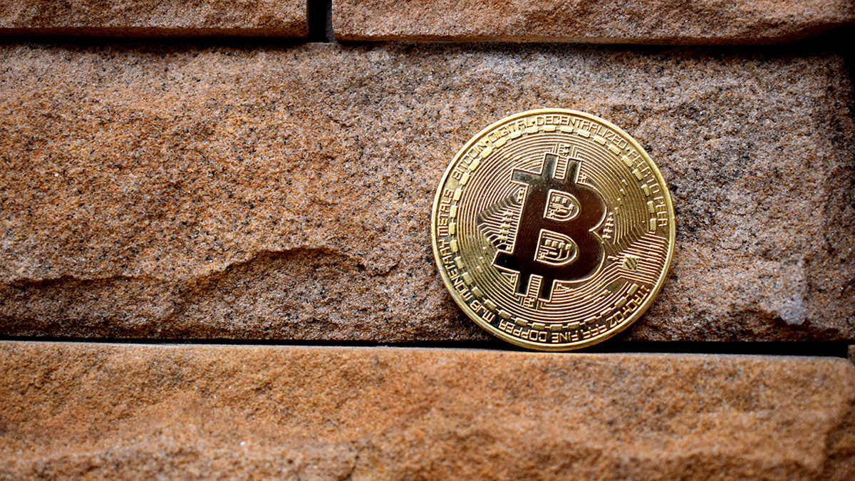 Ett bitcoin-mynt uppställt på en stenmur.