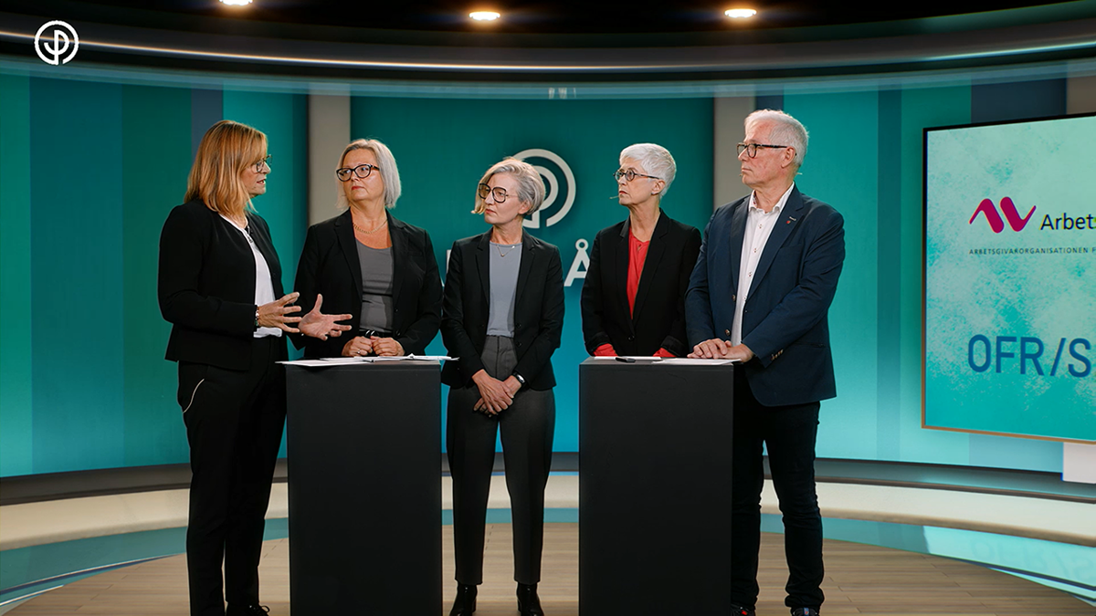 Fem personer samlade runt två svarta pulpeter i direktsändning.