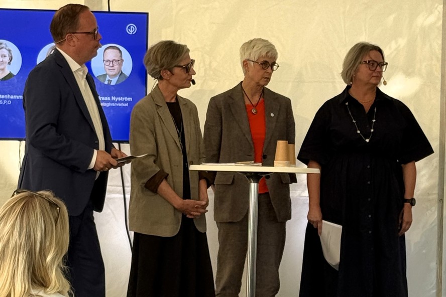 Fyra personer står i ett tält på ett seminarium. 