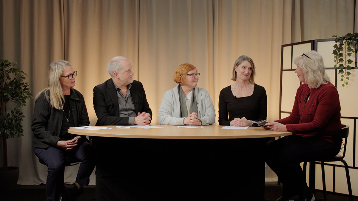 Fem personer sitter runt ett bord i en studio.