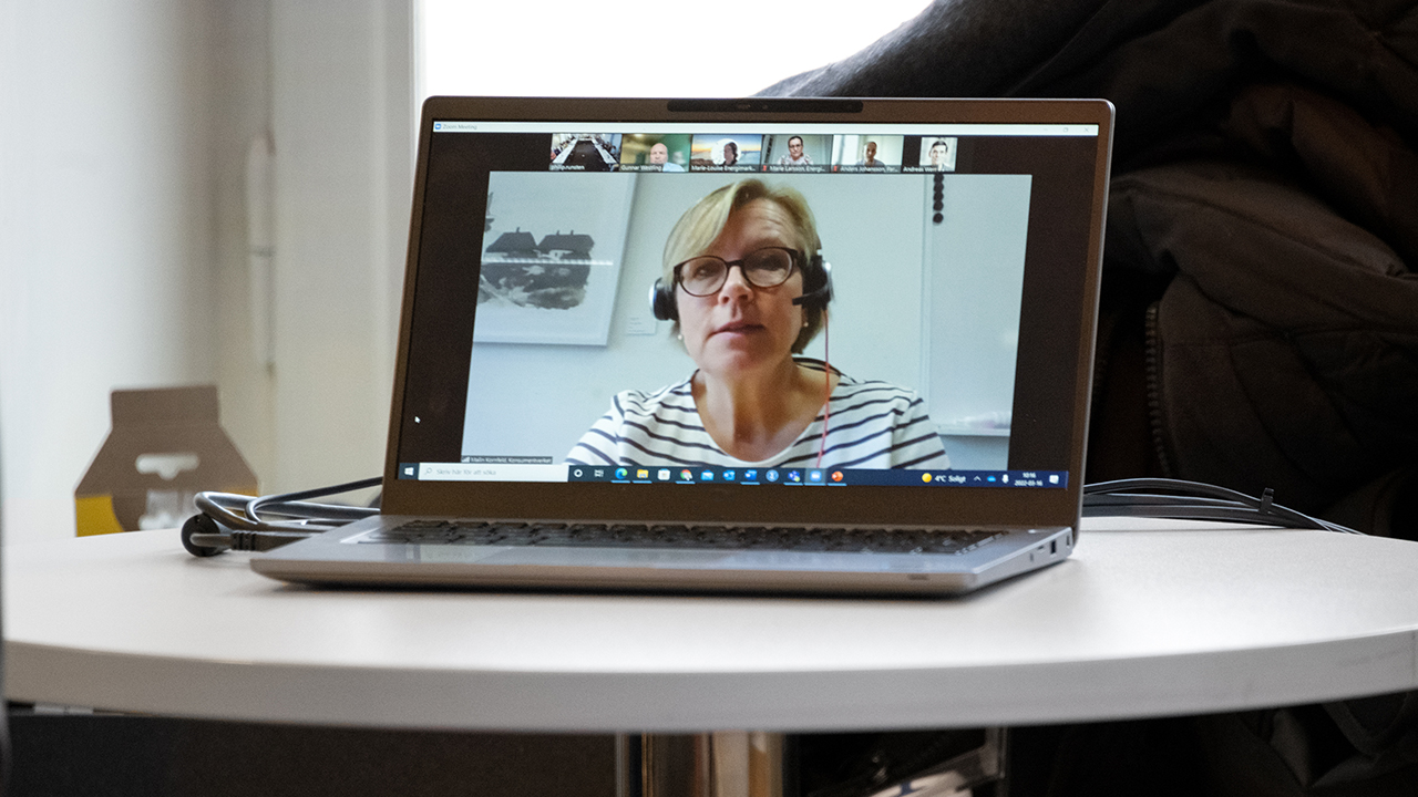 En person som deltar i mötet via Zoom (syns i dator som står på ett bord).