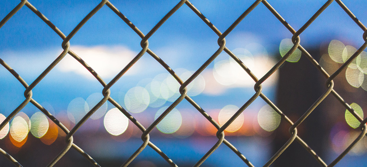 Staket mot en grumlig bakgrund som föreställer stadsmiljö.