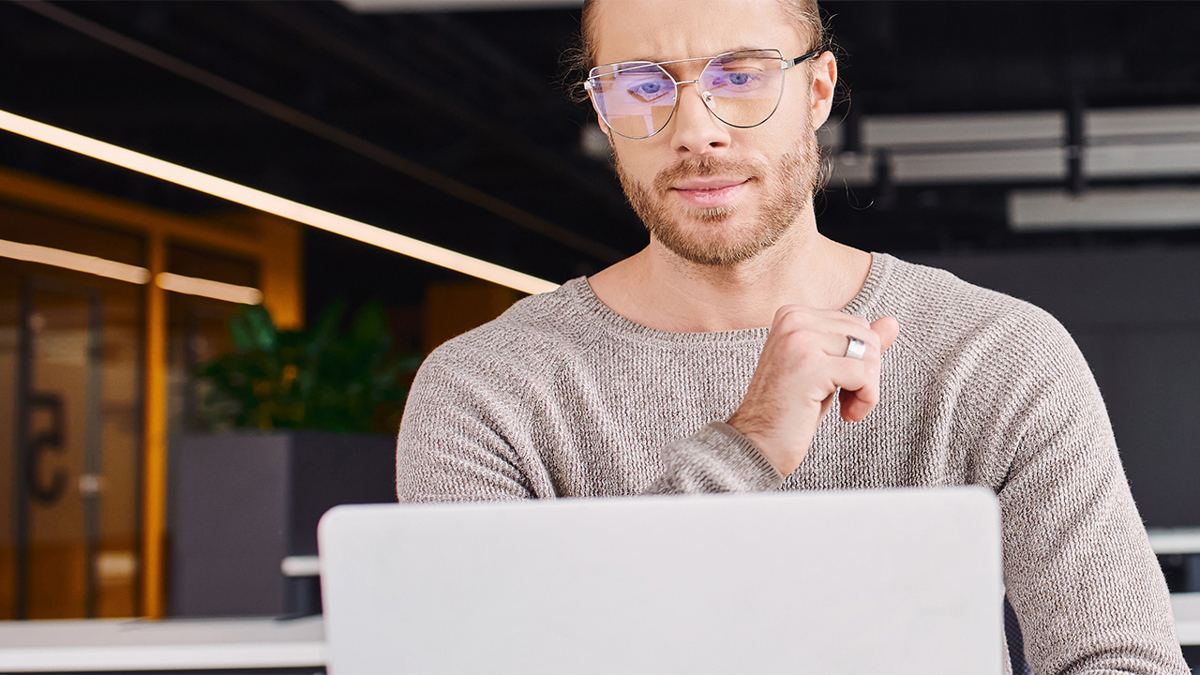 person i kontorslandskap sitter vid laptop