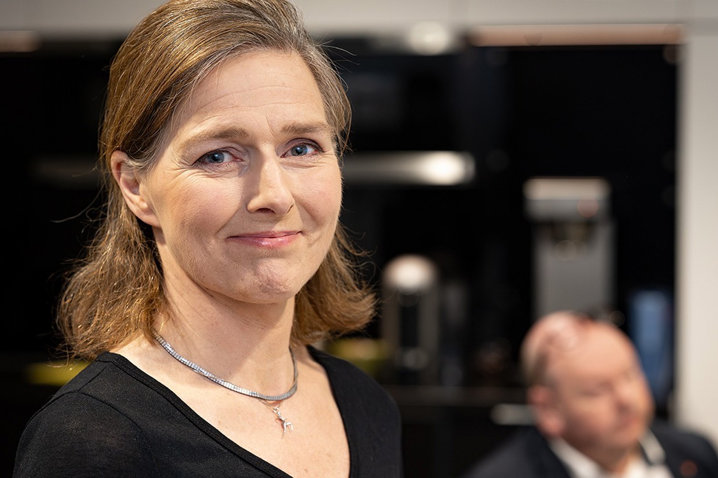 Person iförd svart tröja och silverhalsband.